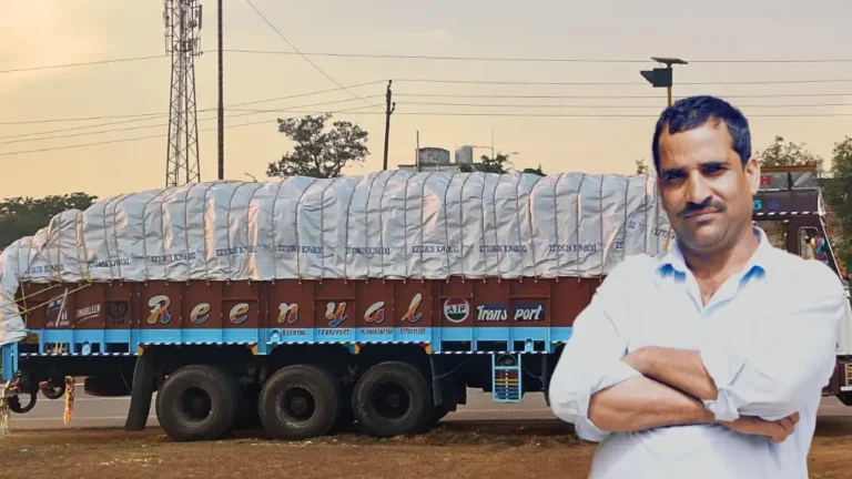 Truck driver smiling next to a truck covered with a high-quality tarpaulin, highlighting its effectiveness in securing cargo during transport.